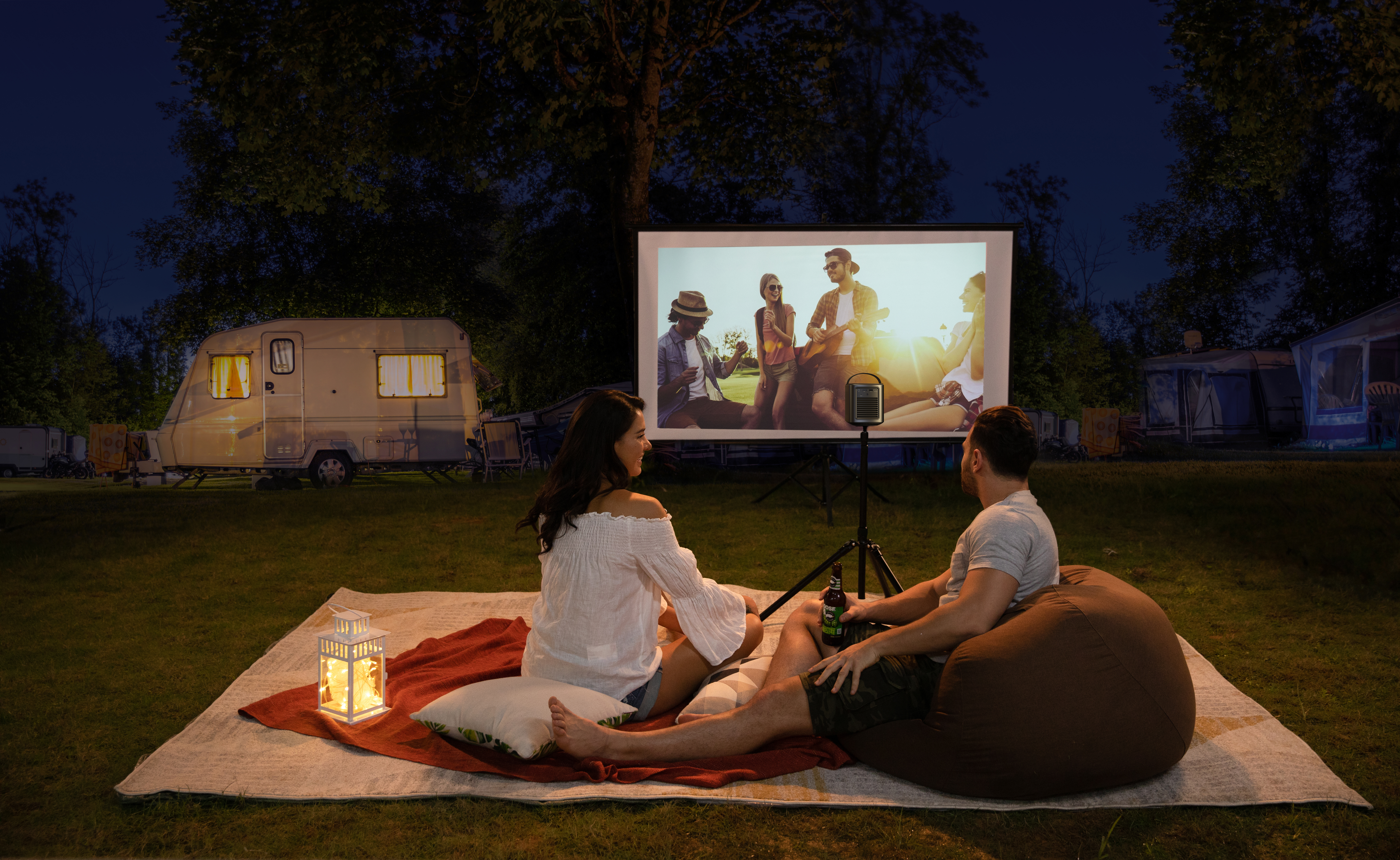 Çift gece kamp sahnesinde bir ekranda film izliyor.