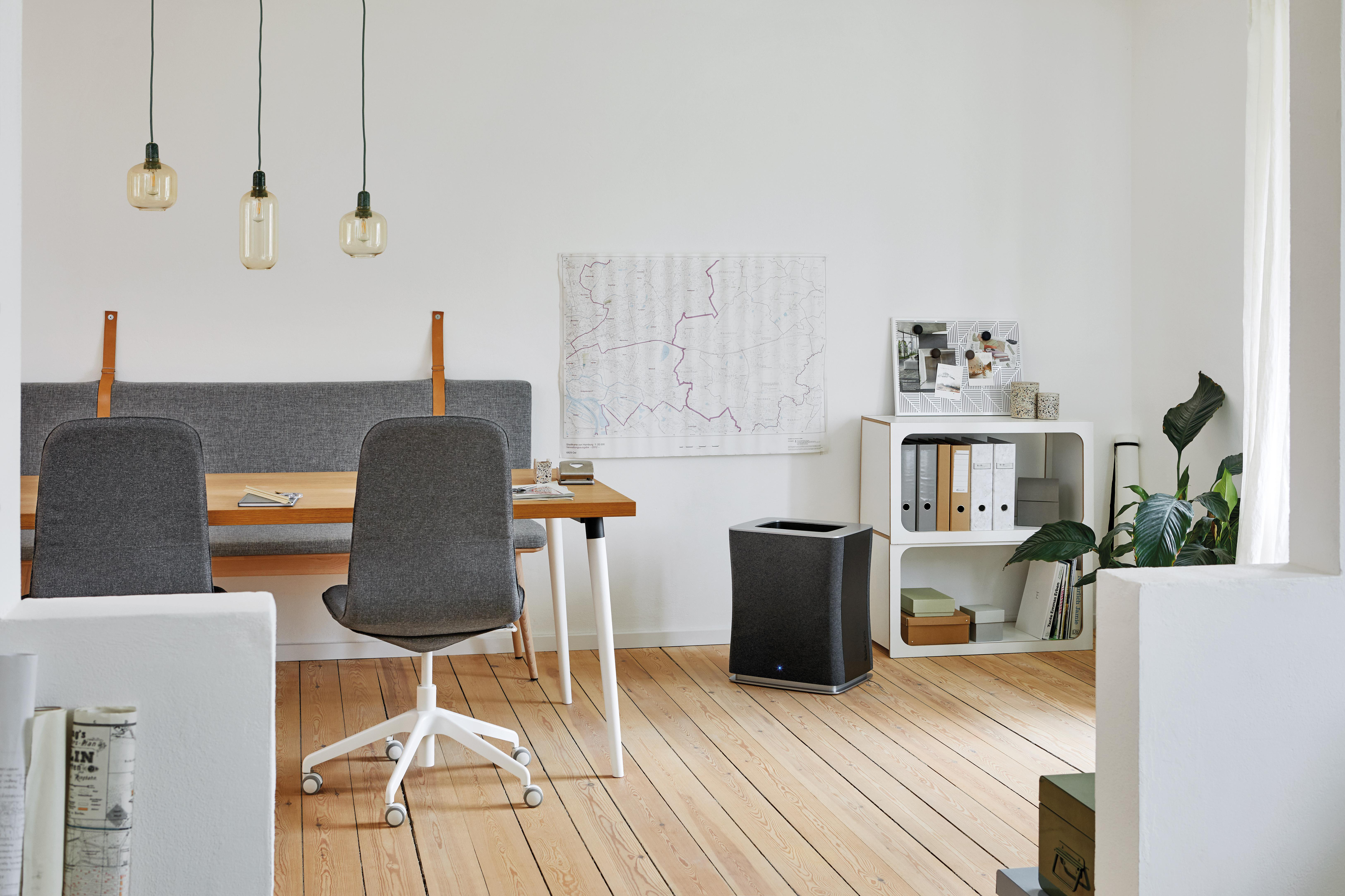 Büro-Innenraum. Luftreiniger in der Nähe des Schreibtischs, Karte an der Wand, Holzboden.