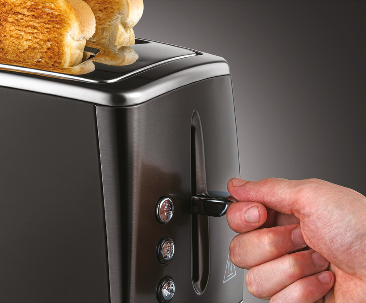 Toaster with bread. A hand is pulling the lever down. The toaster is black and metallic.
