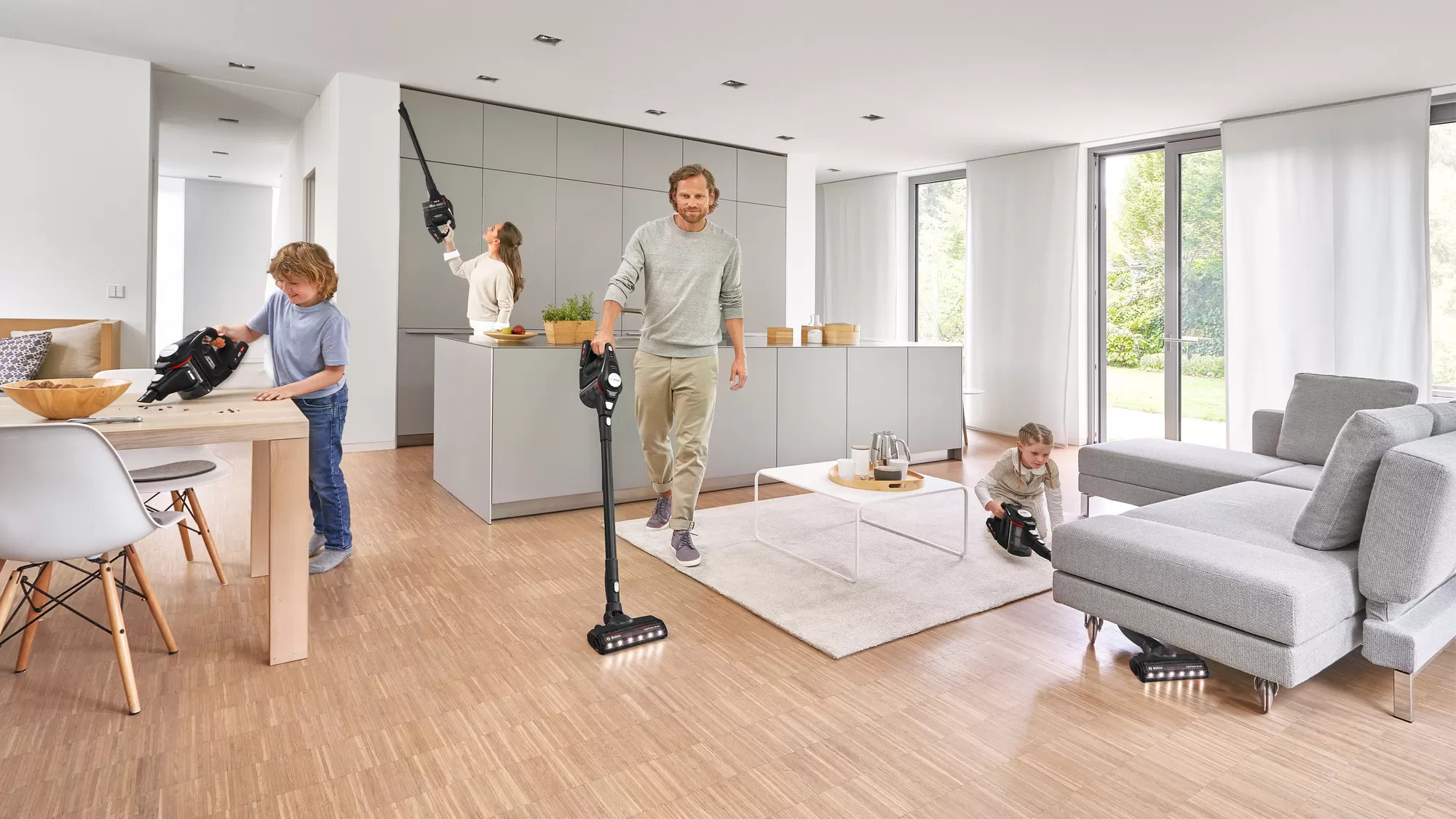 Familie gebruikt stofzuiger. Man en kinderen aan het schoonmaken. Moderne keuken en woonkamer.