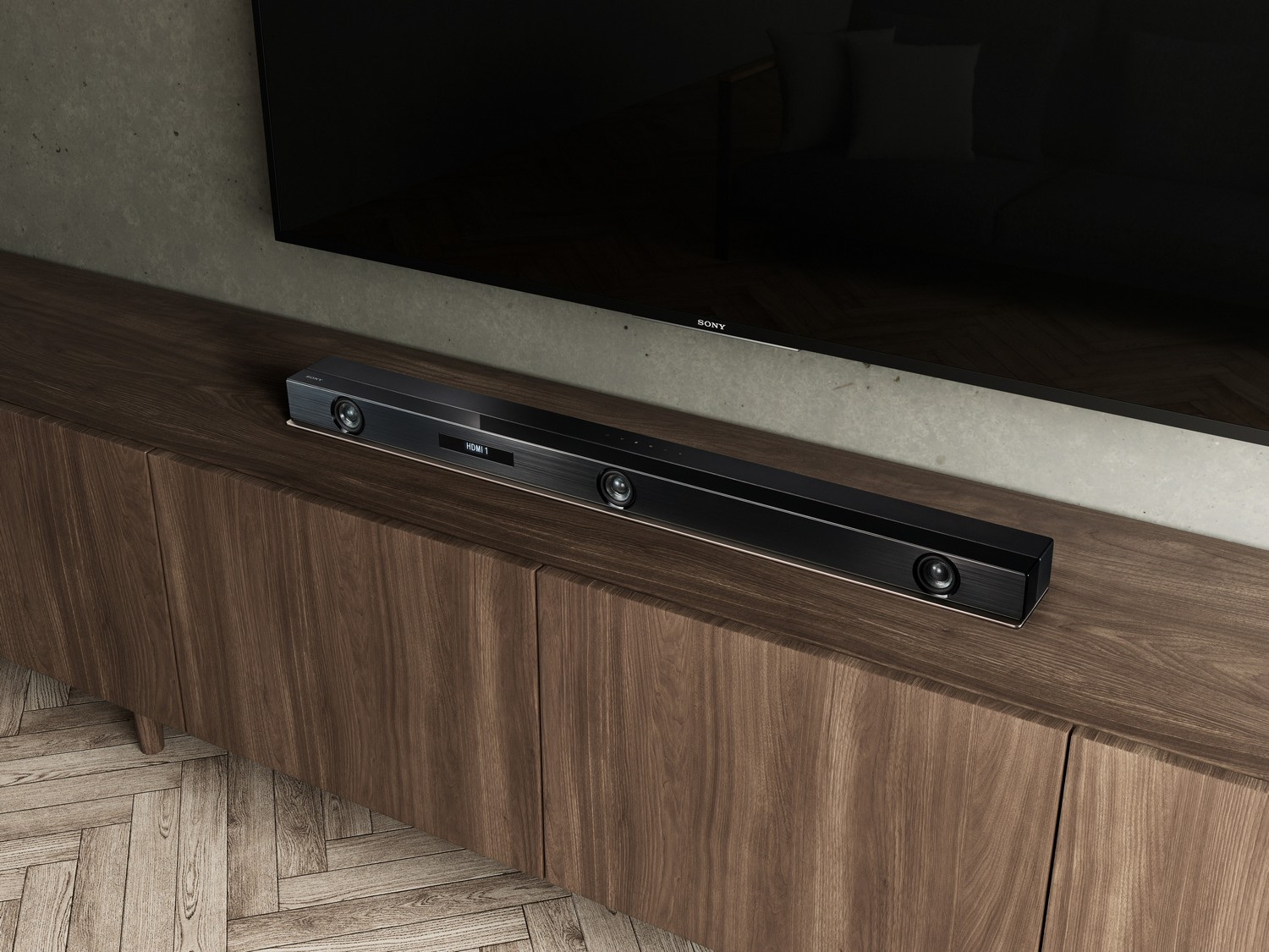 Una barra de sonido se coloca en un mueble de madera debajo de un televisor negro montado en la pared.