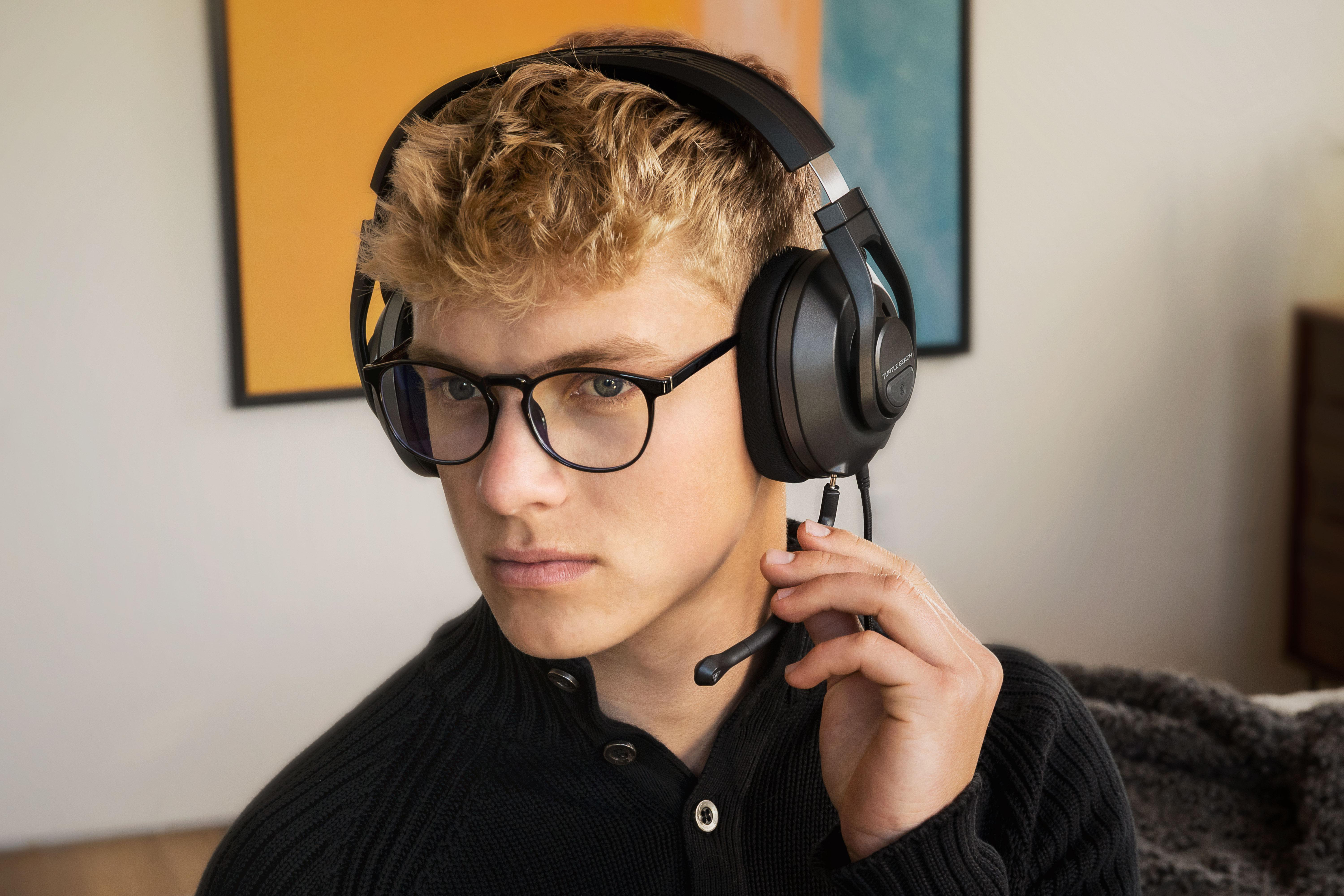 Blonder Teenager mit Brille, Kopfhörern und Mikrofon.