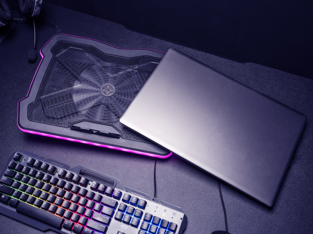 Laptop hűtőpaddal és billentyűzettel, sötét felületen, játék beállítás.