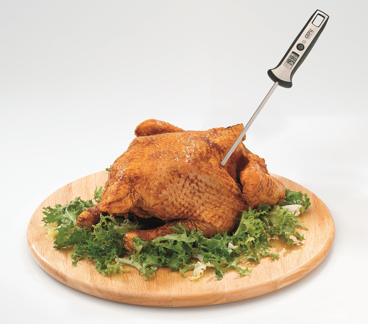 Gebratenes Hähnchen auf einem Holzbrett mit einem Fleischthermometer.