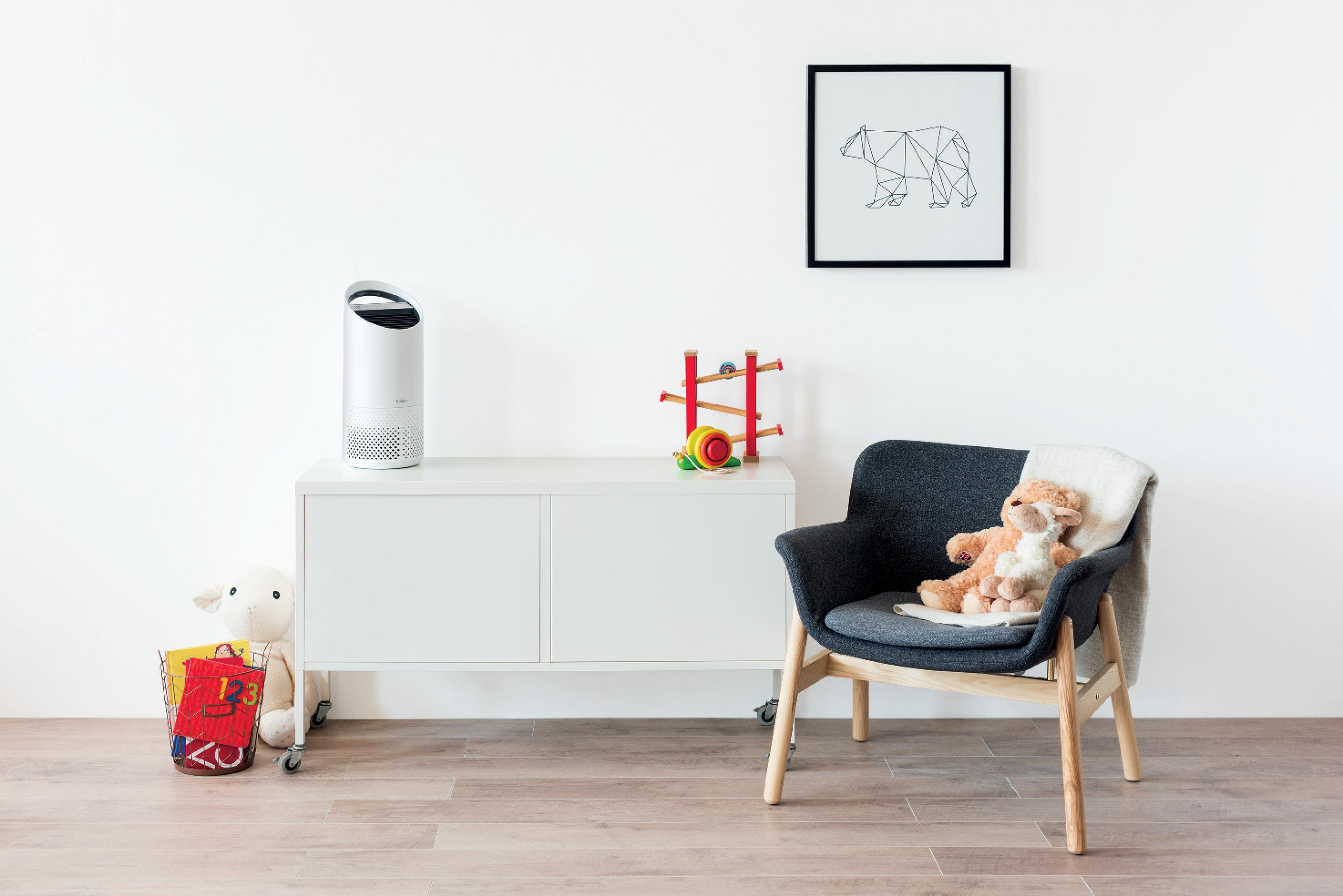 Innenszene. Luftreiniger auf weißem Schrank, Stuhl und Zeichnung an der Wand.