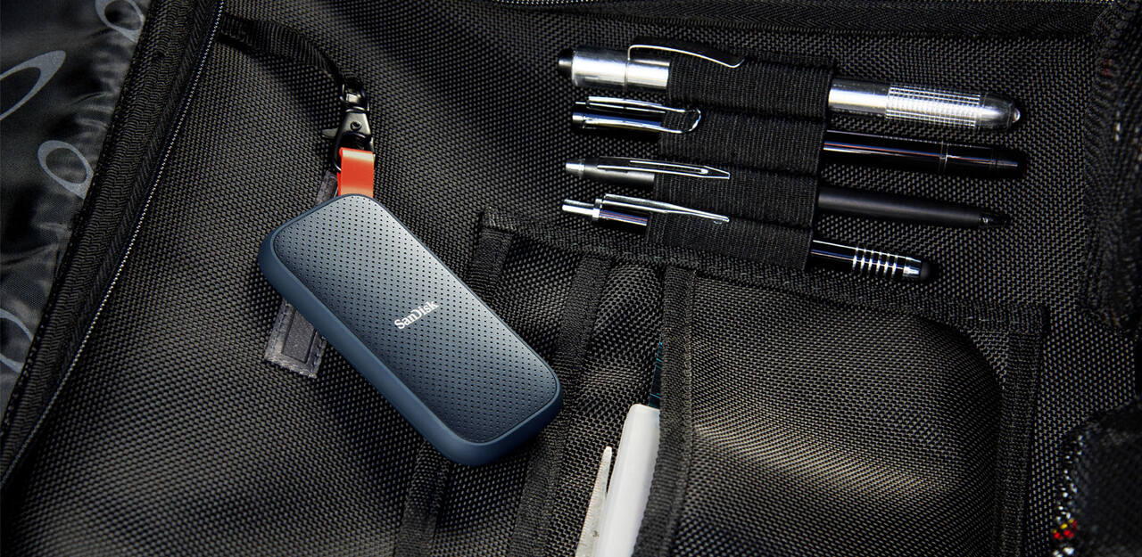 Eine schwarze Tasche mit Stiften und einer externen Sandisk-Festplatte. Die Tasche ist offen.