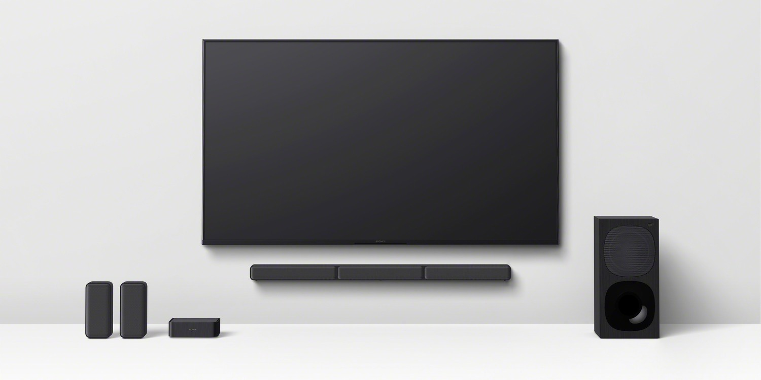 TV en la pared con barra de sonido, subwoofer y altavoces traseros.