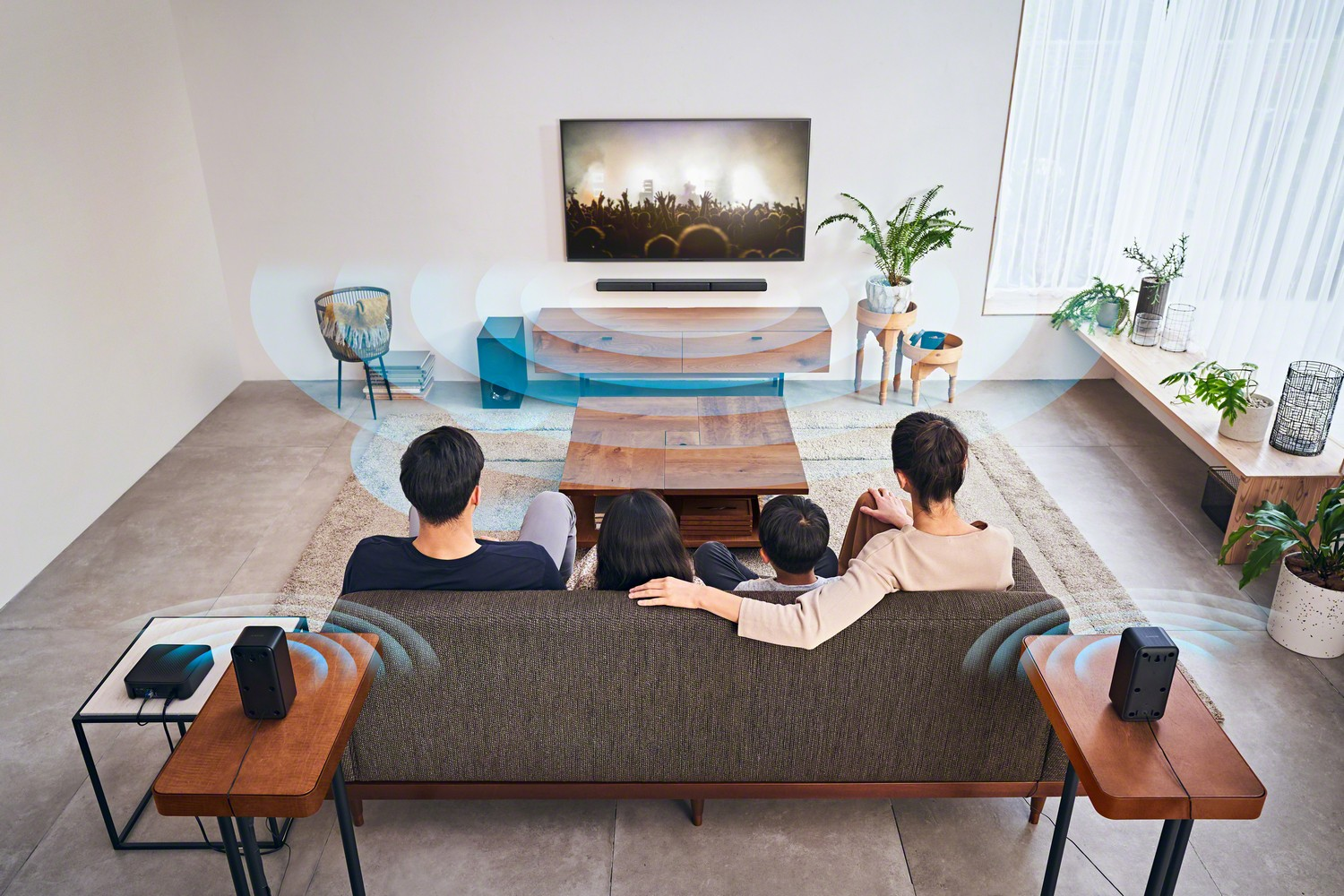 Una familia ve la televisión en un sofá, con dos altavoces a cada lado y gráficos de ondas sonoras.