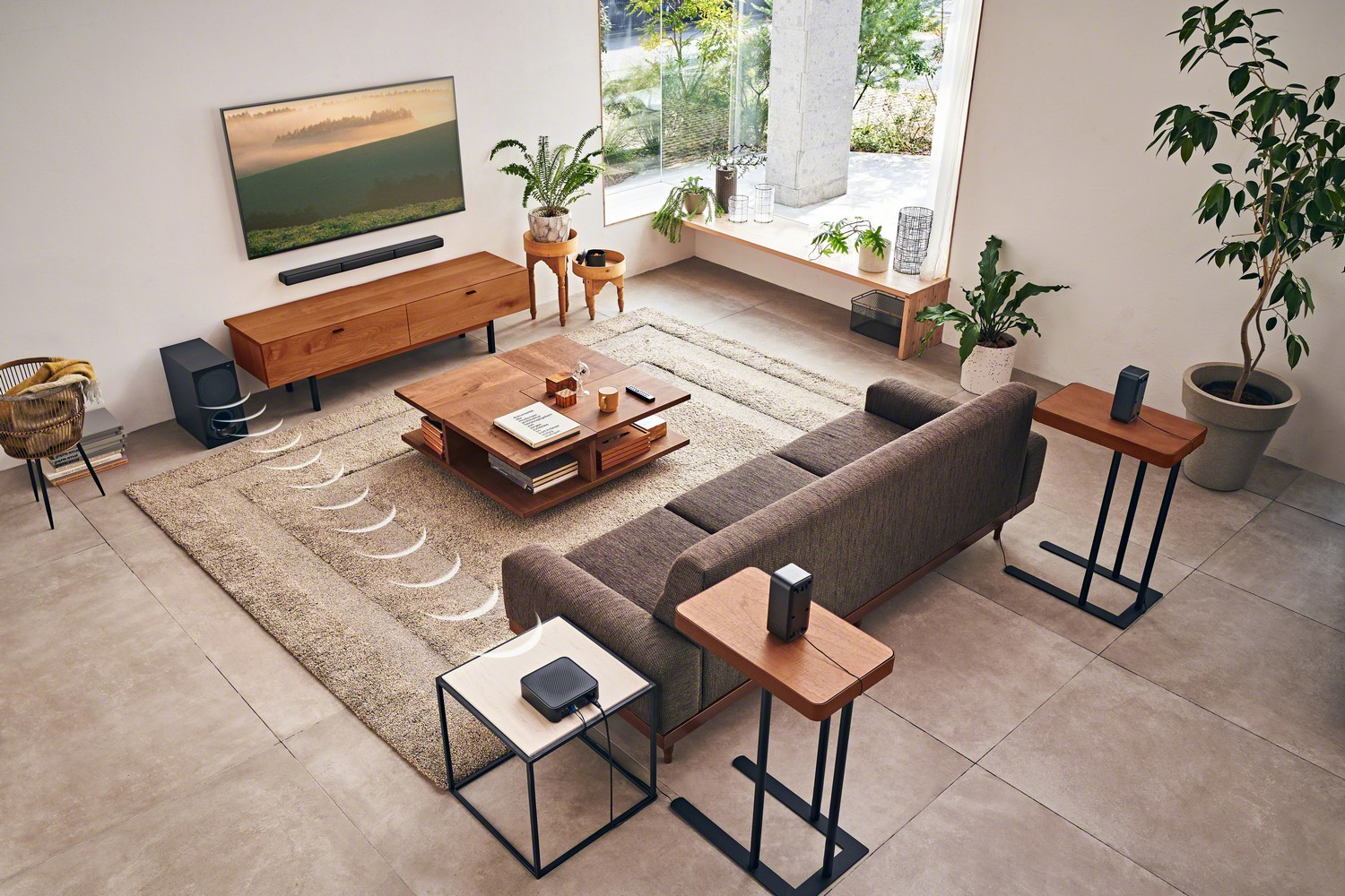 Salón con sofá, altavoces, TV y muebles. La habitación está bien iluminada y tiene plantas.
