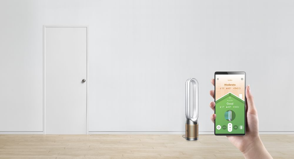 Raumszene mit Luftreiniger und Person, die ein Tablet mit Luftqualitätsdaten hält.