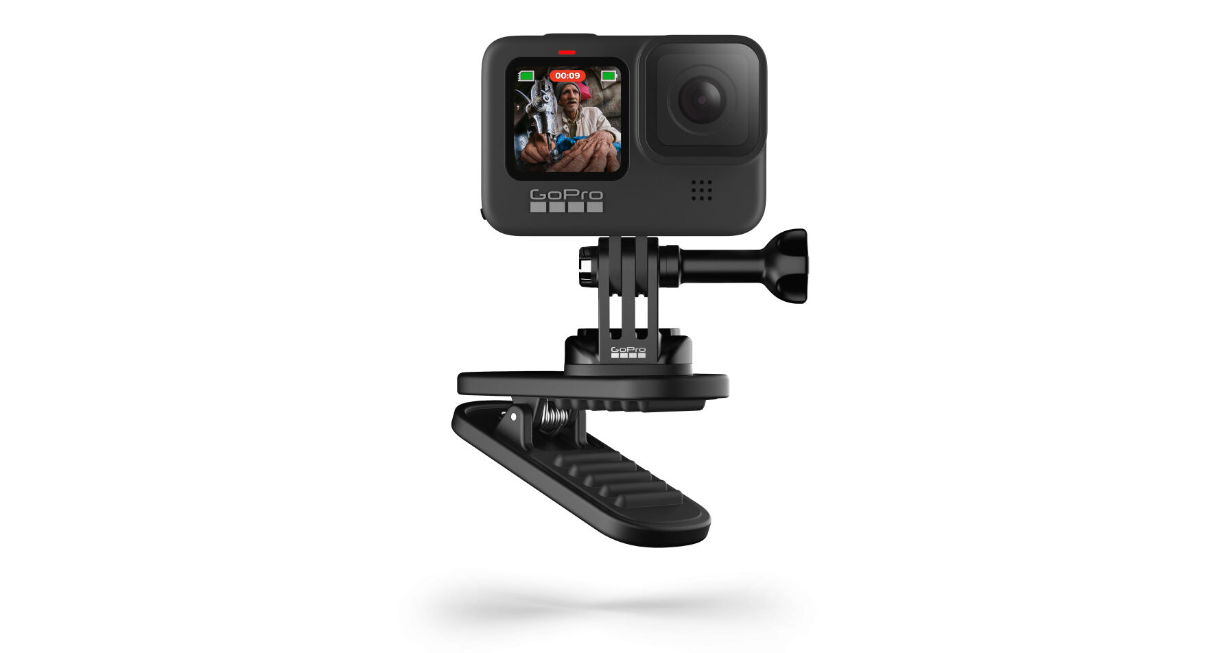 Fekete GoPro kamera egy klipszen. A képernyőn egy személy látható. Fehér háttér.