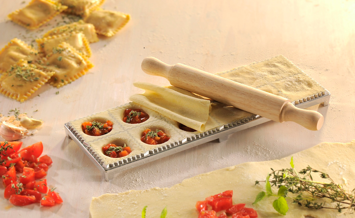 Ravioli-Zubereitung mit Ravioli, Tomaten, Nudelholz und Teig.