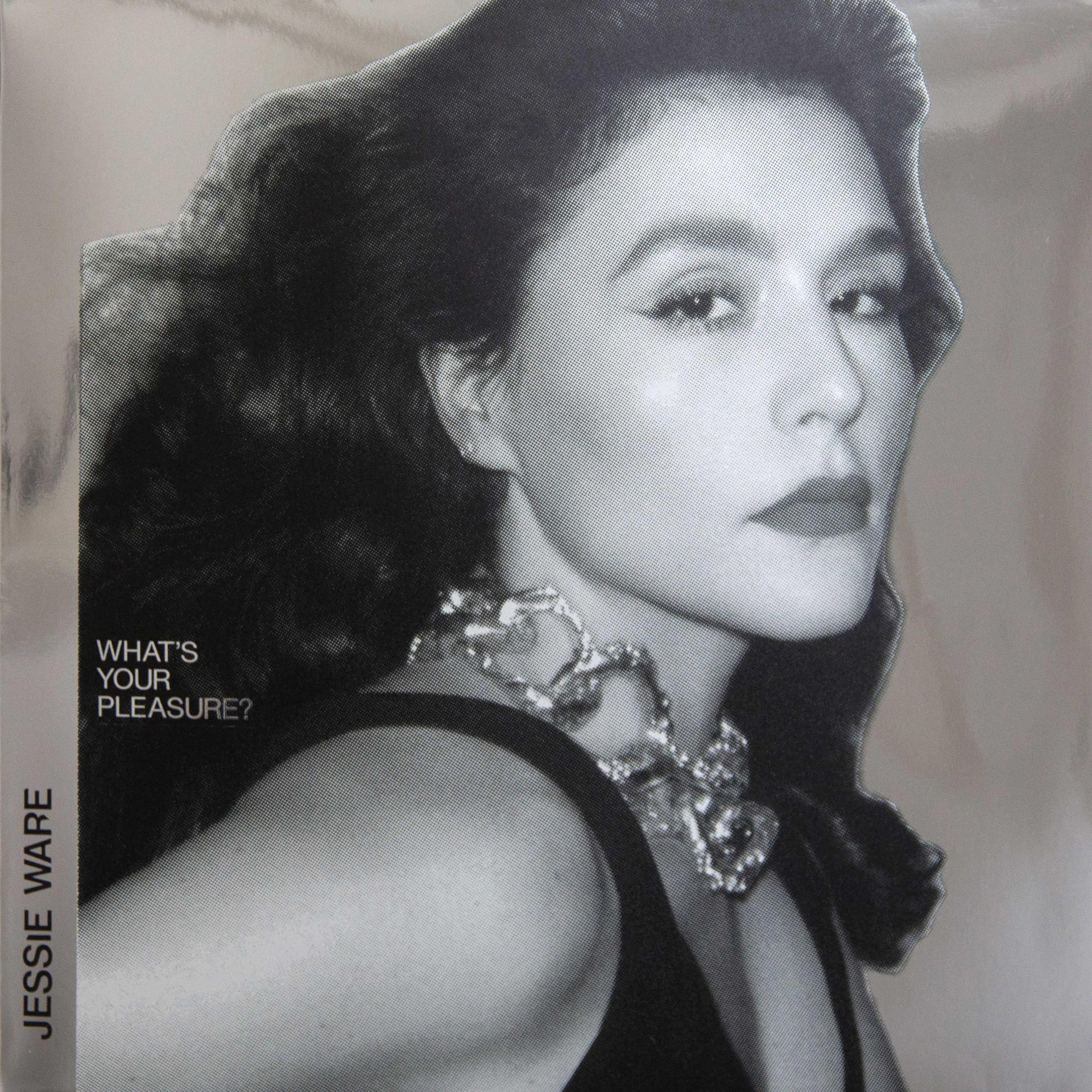 Ein Schwarzweißfoto von Jessie Ware mit Halskette. Die Worte 'WHAT'S YOUR PLEASURE?' sind sichtbar.