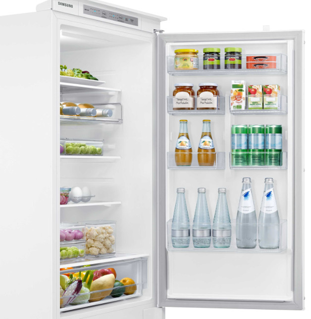 Open koelkast met voedsel, potten, flessen en verse producten. Wit interieur en RVS details.