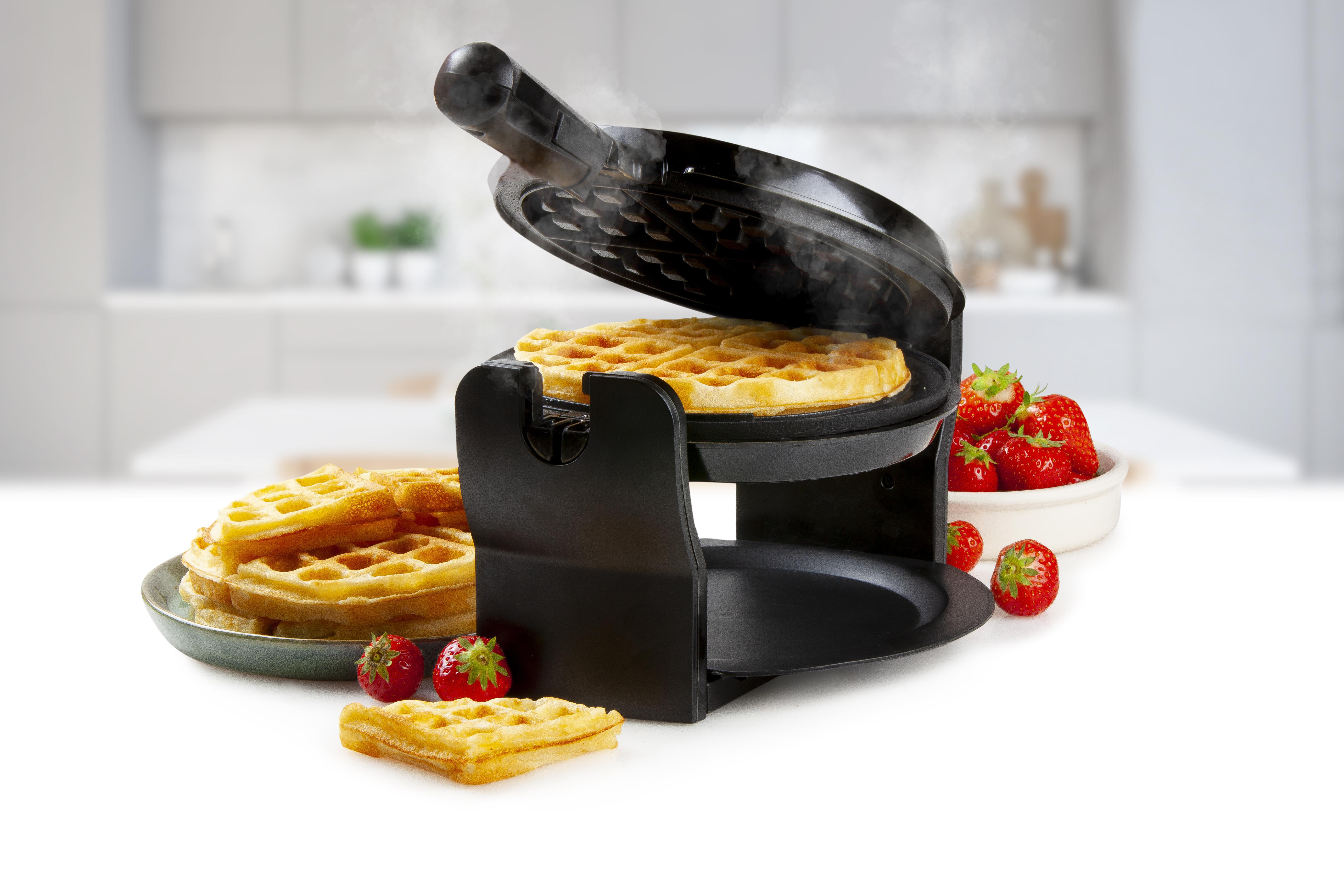 Waffeleisen mit Waffeln, Erdbeeren und einem Teller Waffeln.