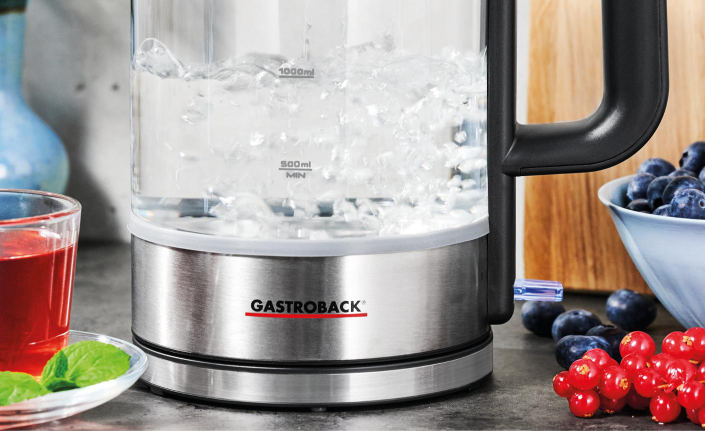Glaskessel mit kochendem Wasser, rotem Getränk und Blaubeeren. Gastroback Logo sichtbar.