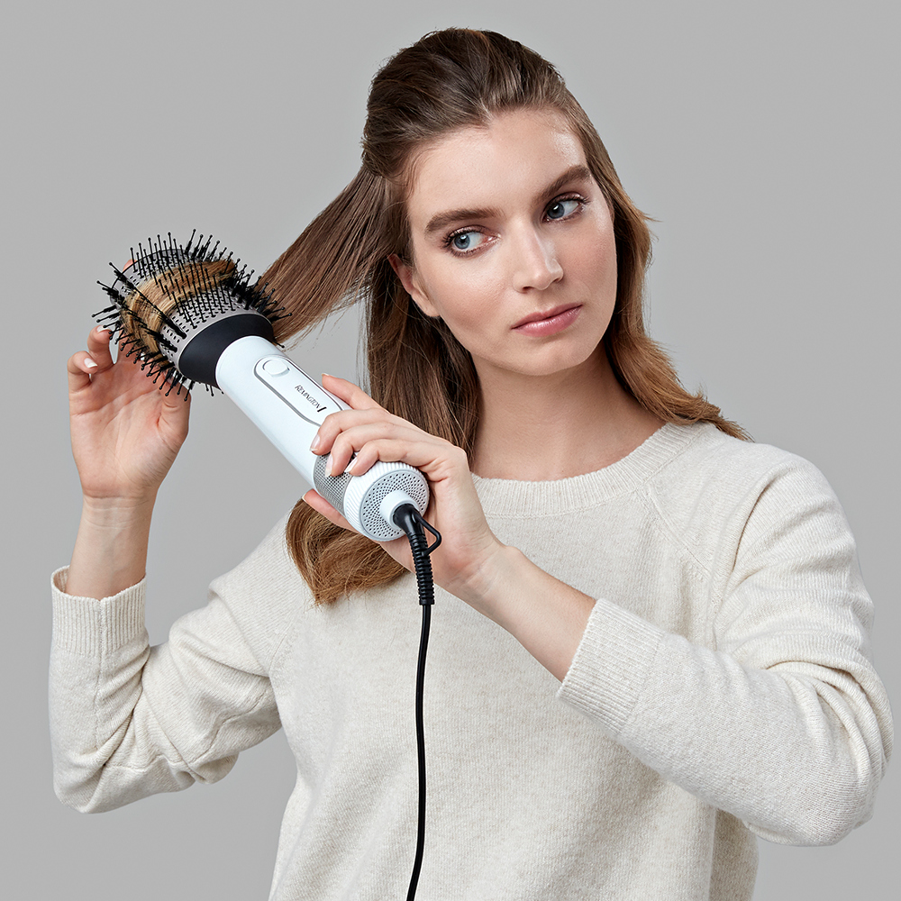 Woman using a hair dryer brush on her hair.