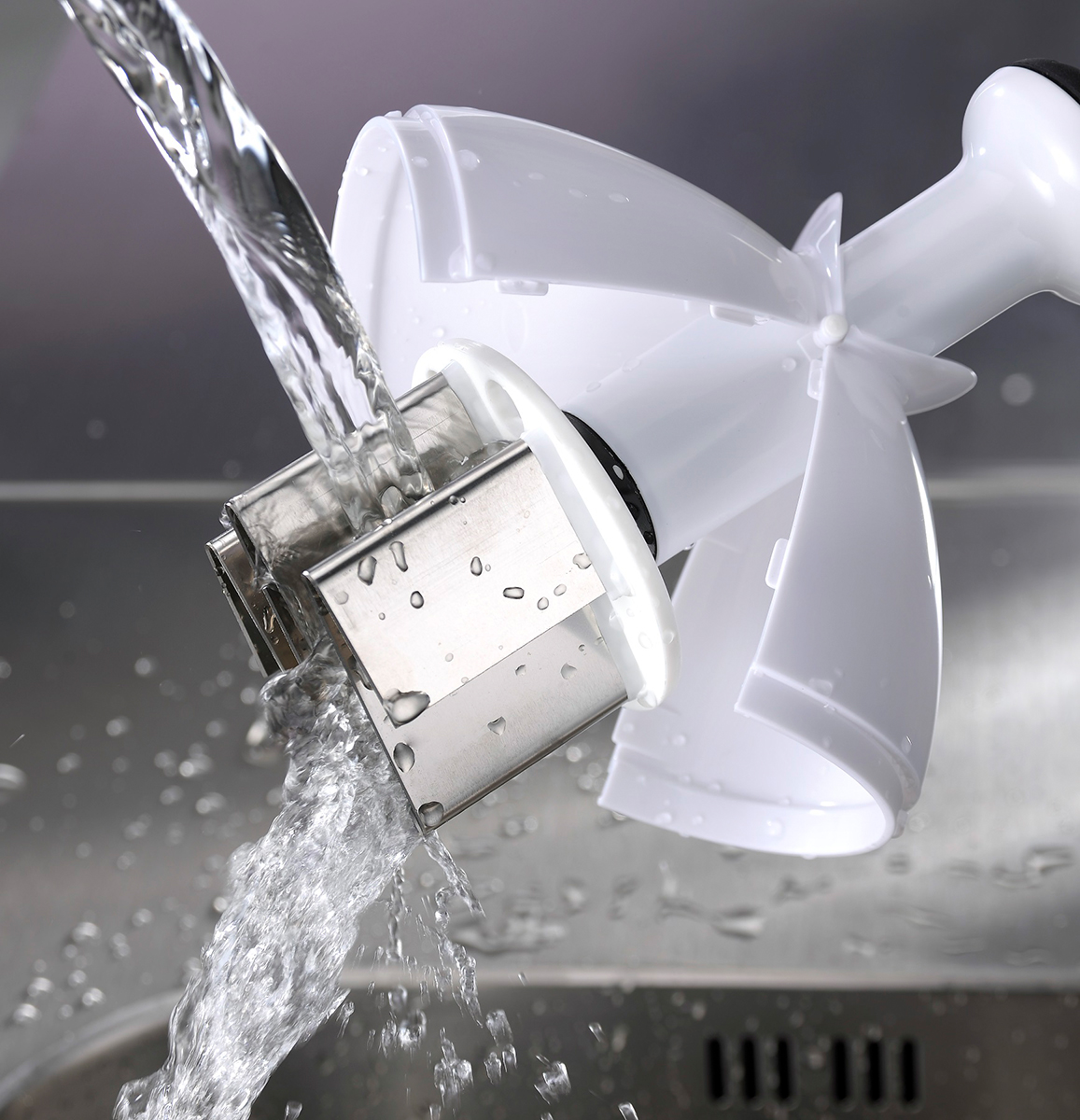 Wasser, das über ein weißes Küchengerät mit Metallgitter gegossen wird.