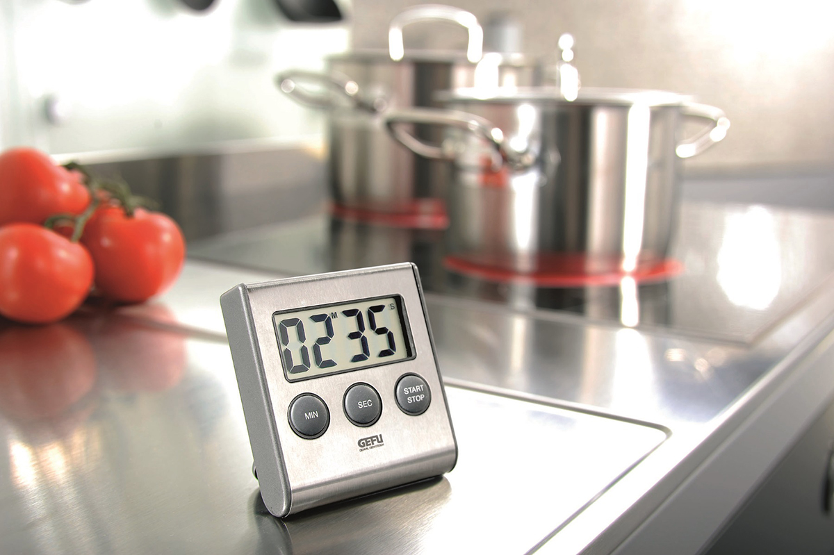 Silberner Küchentimer mit Zahlen auf dem Display, auf einer Edelstahloberfläche.