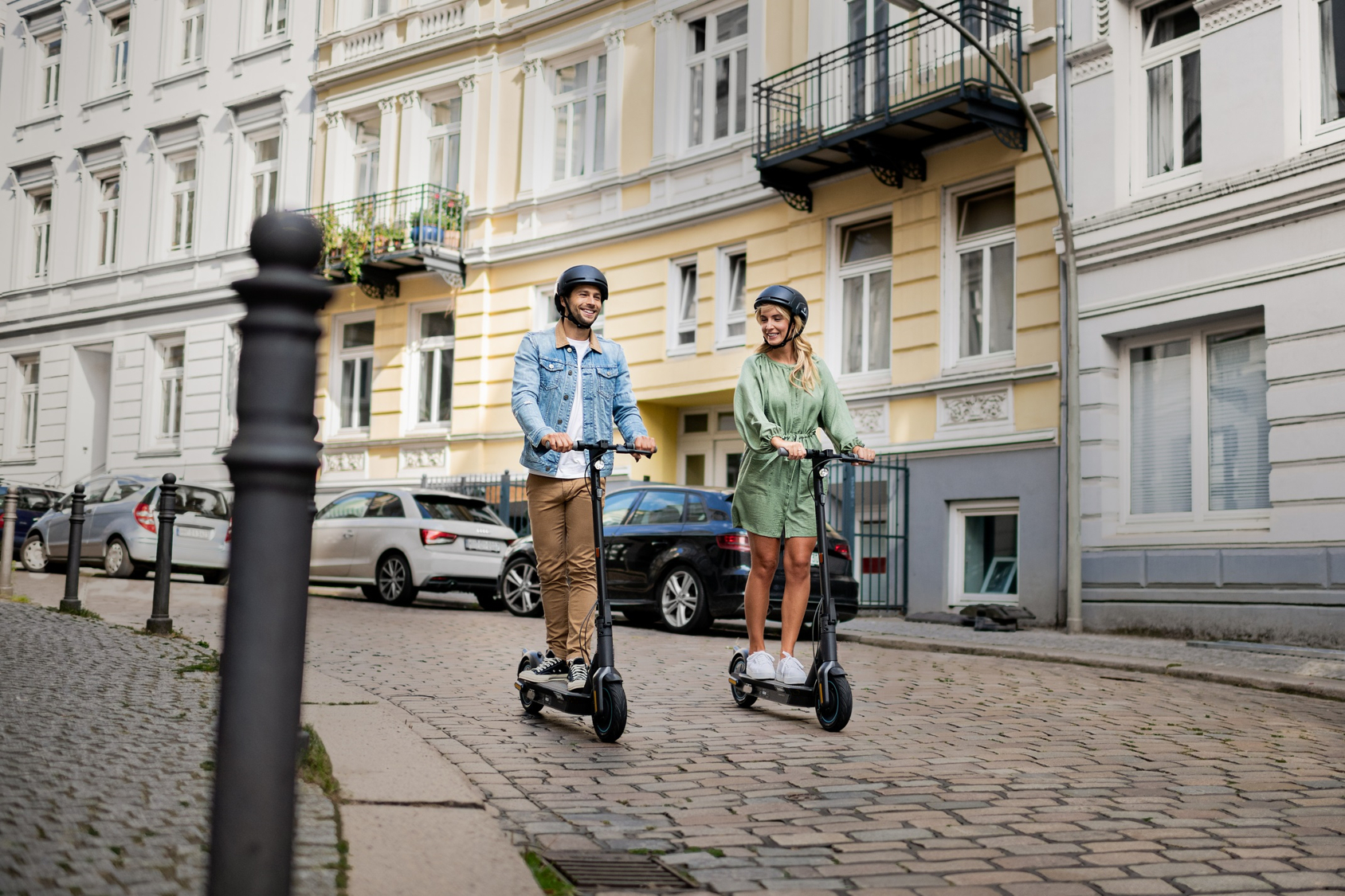 Zwei Personen fahren mit Elektrorollern auf einer Stadtstraße.