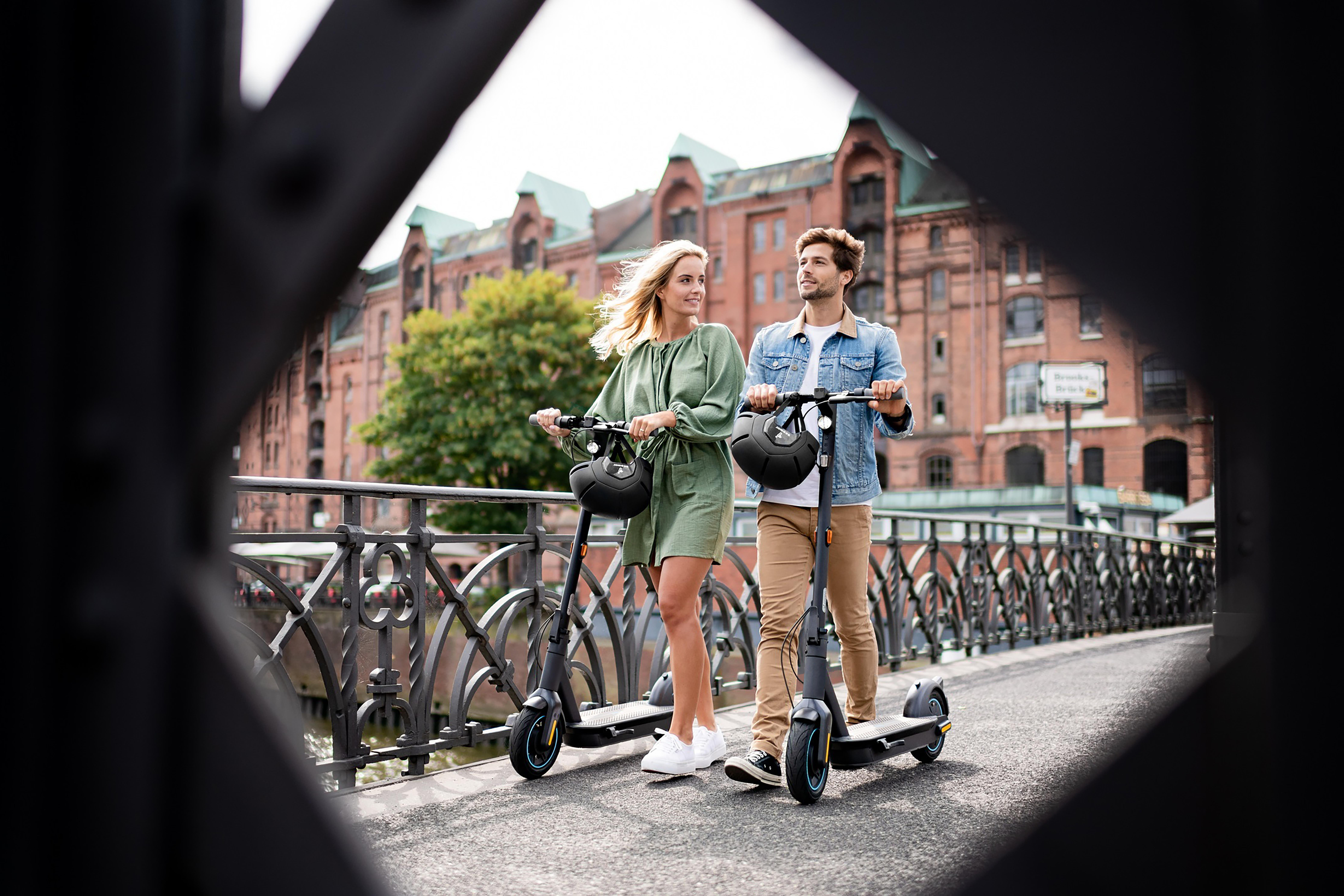 Paar fährt Roller auf einer Brücke in einer Stadt.