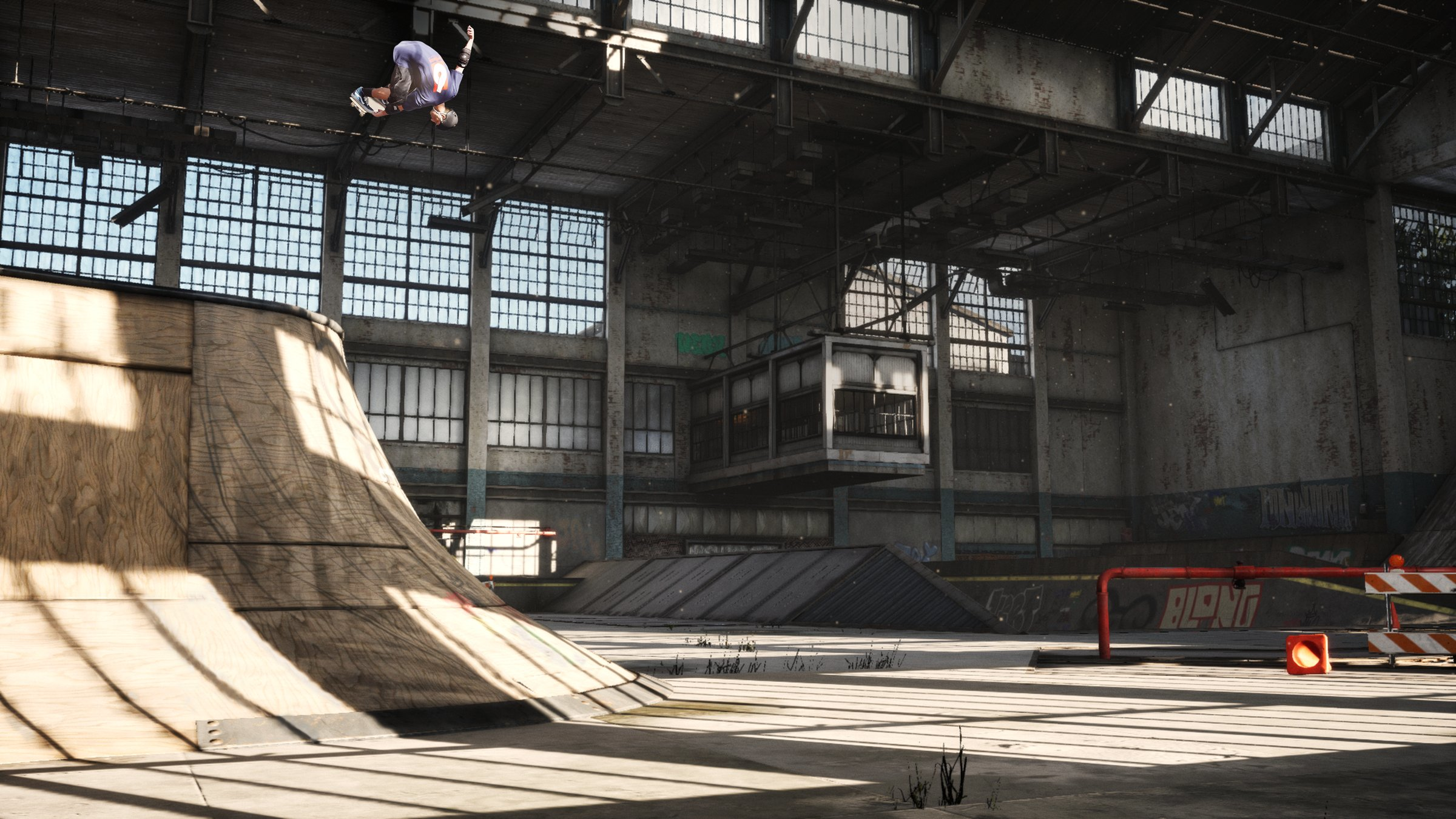 Ein Skateboarder in der Luft über einer Rampe in einem Lagerhaus.