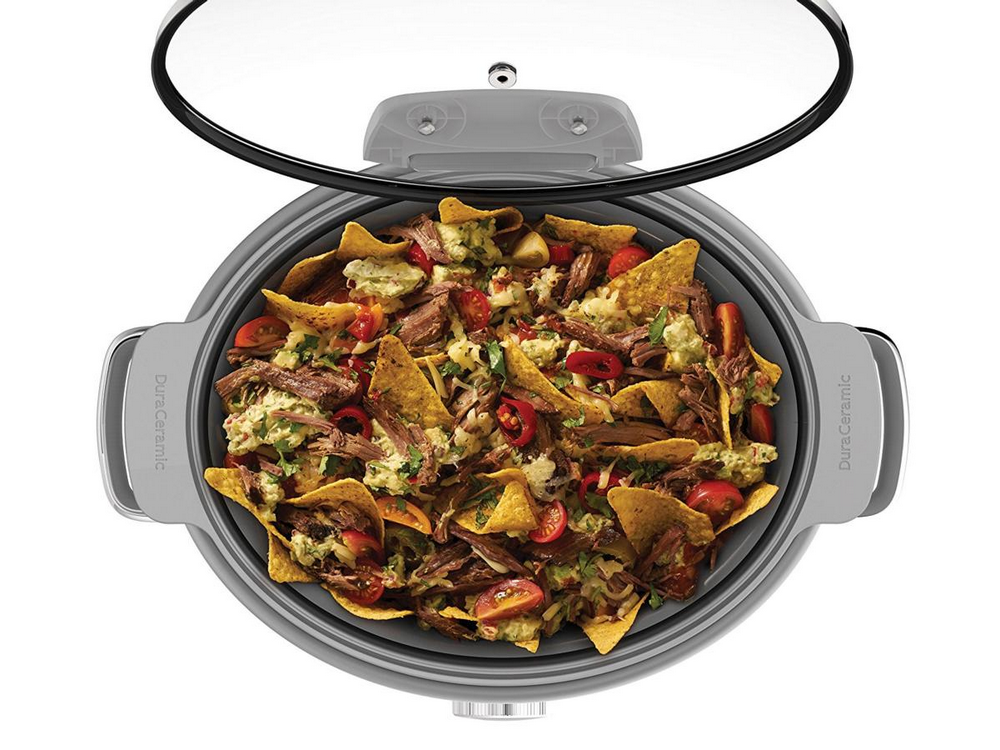 Vista superior de una olla de cocción lenta con nachos: chips de tortilla, carne, tomates, guacamole y cilantro.