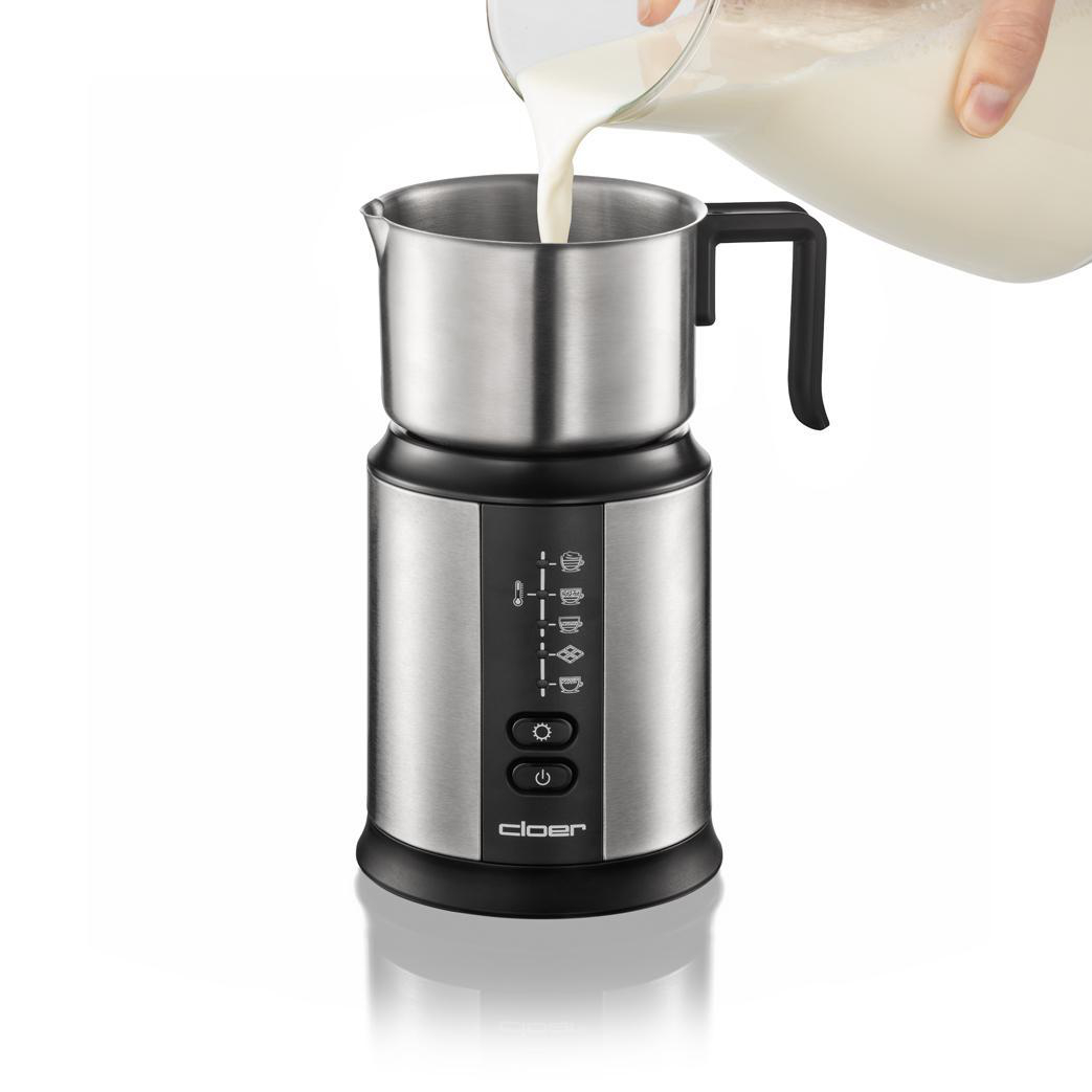 Milch wird in einen Milchaufschäumer aus Edelstahl gegossen.