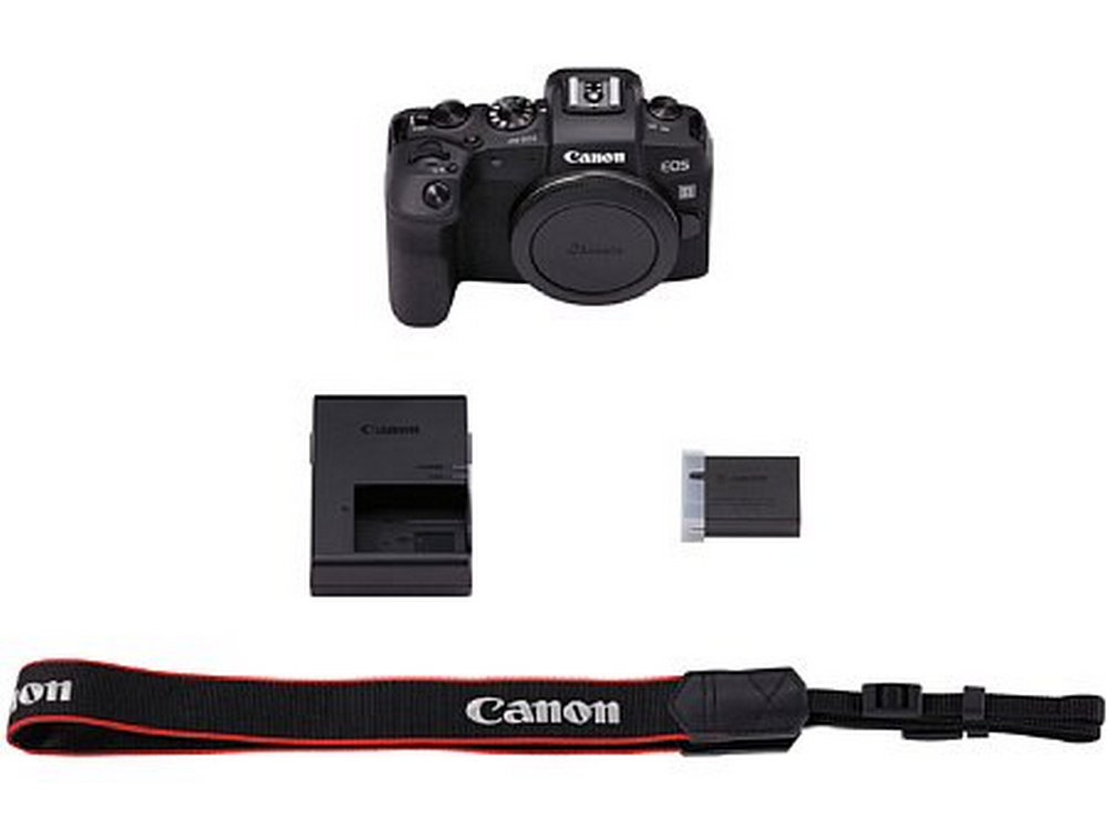 Una cámara Canon, cargador de batería, batería y correa sobre blanco.