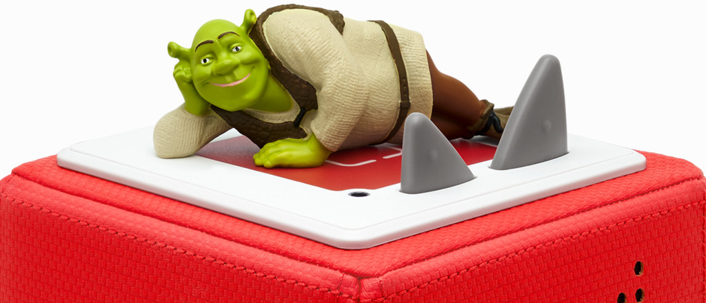Shrek-Spielzeug auf einem roten Block mit grauen Haifischflossen.