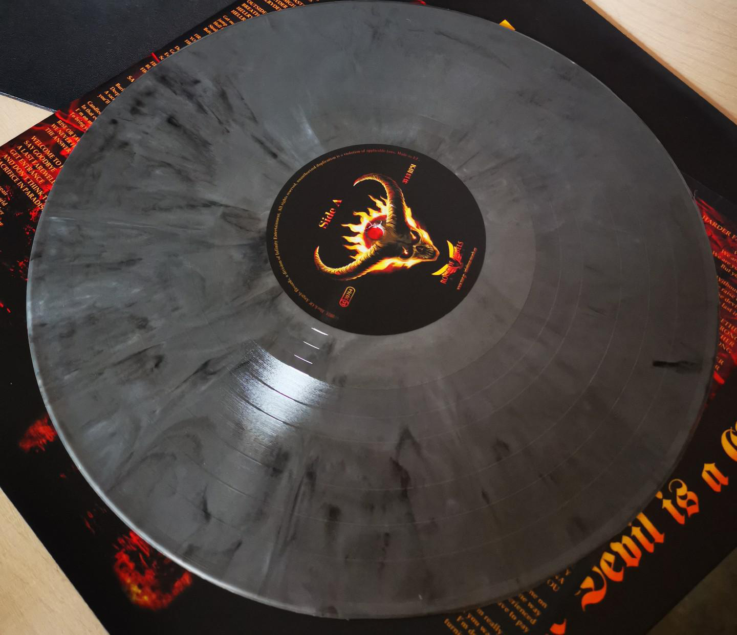 Vinylplatte mit schwarz-grauem Marmordesign und farbenfrohem Etikett. Schwarzer Hintergrund.