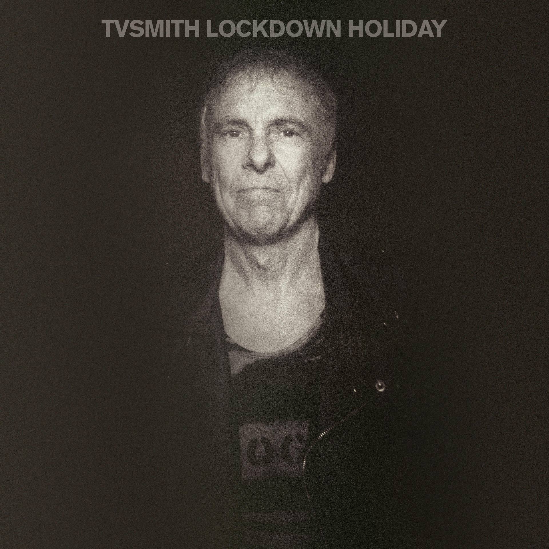 Schwarz-Weiß-Foto eines Mannes, der nach vorne schaut, mit dem Titel 'TVSMITH LOCKDOWN HOLIDAY' oben.
