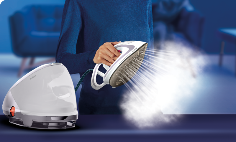 A woman ironing with steam from a white iron, next to a white steam generator.