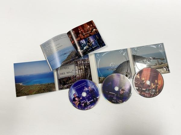 Offene CD-Hülle mit CDs und Broschüre. CDs haben Bilder von Musikern und Landschaft.