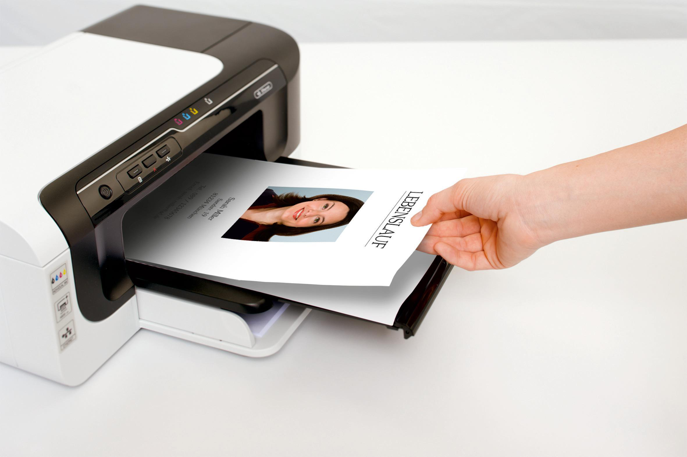 Die Hand einer Person nimmt einen Lebenslauf aus einem Drucker.