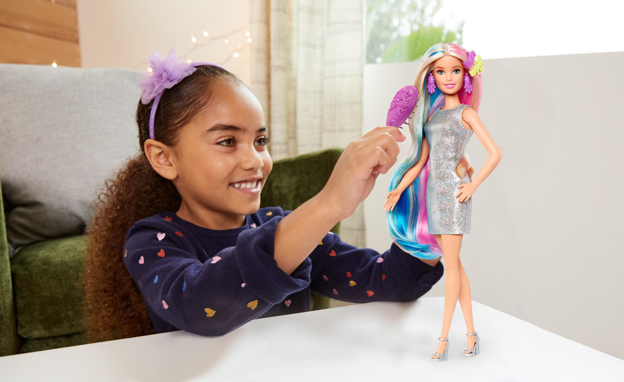 Ein junges Mädchen spielt mit einer Barbie-Puppe und Zubehör.