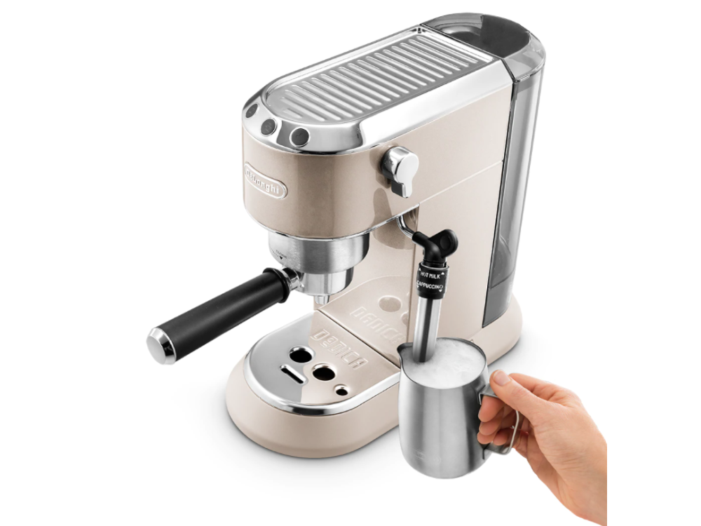 Una máquina de espresso DeLonghi beige con acabado cromado. Una mano sostiene una jarra para espumar leche.