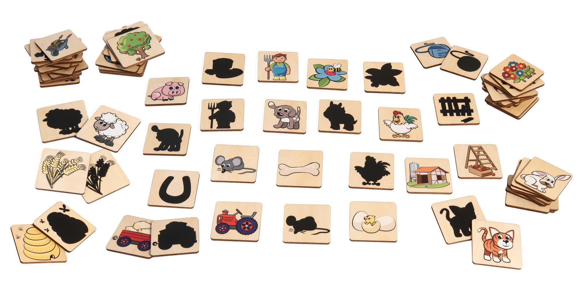 Holzspielsteine mit Bauernhofmotiven, verstreut auf einer weißen Oberfläche. Das Spiel beinhaltet passende Paare.