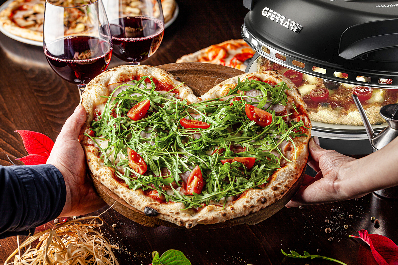 Herzförmige Pizza mit Rucola und Tomaten, Hände halten sie, Ofen in der Nähe.