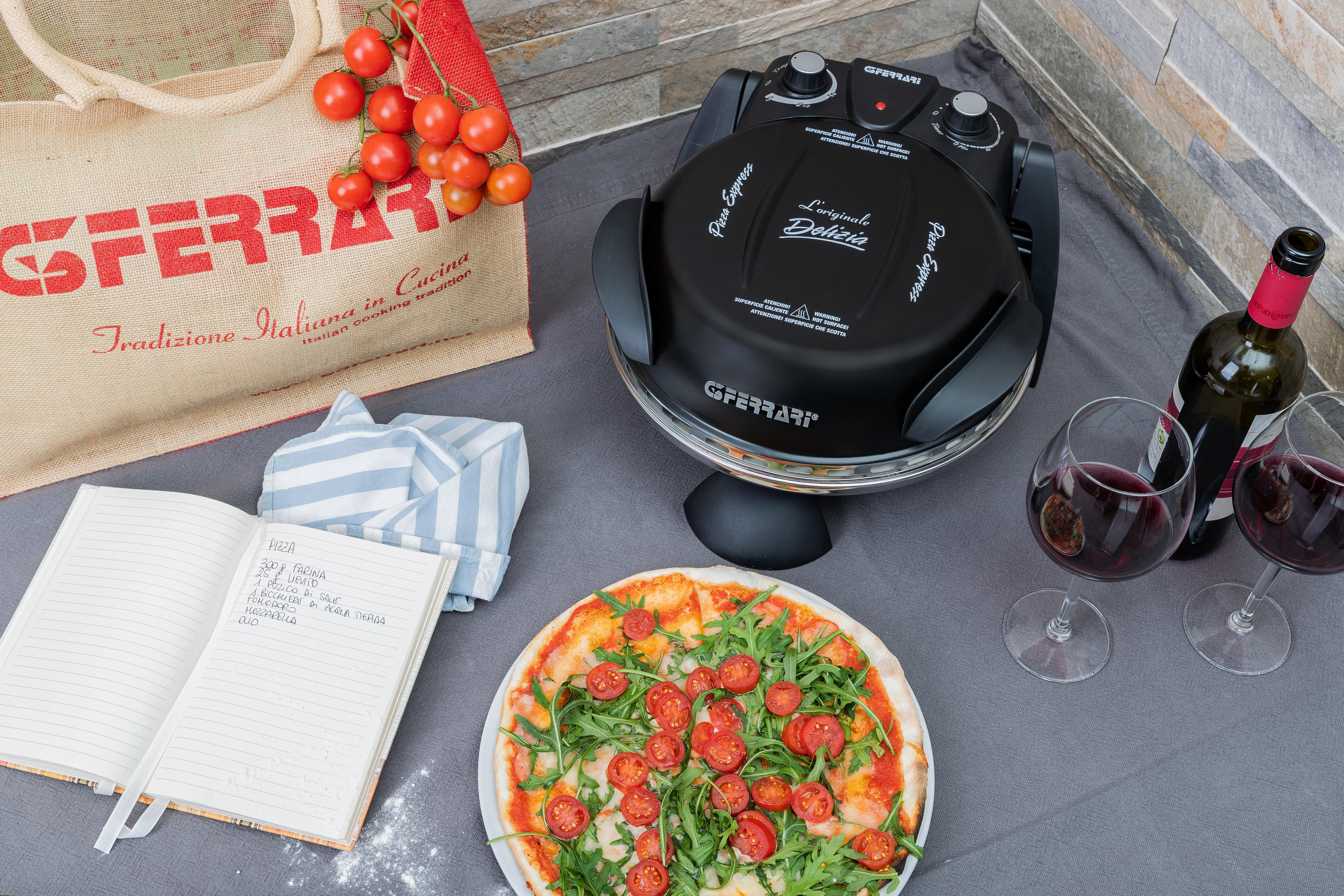 Eine Pizza mit Rucola und Tomaten auf einem Teller, Weingläser, Weinflasche und Notizblock.