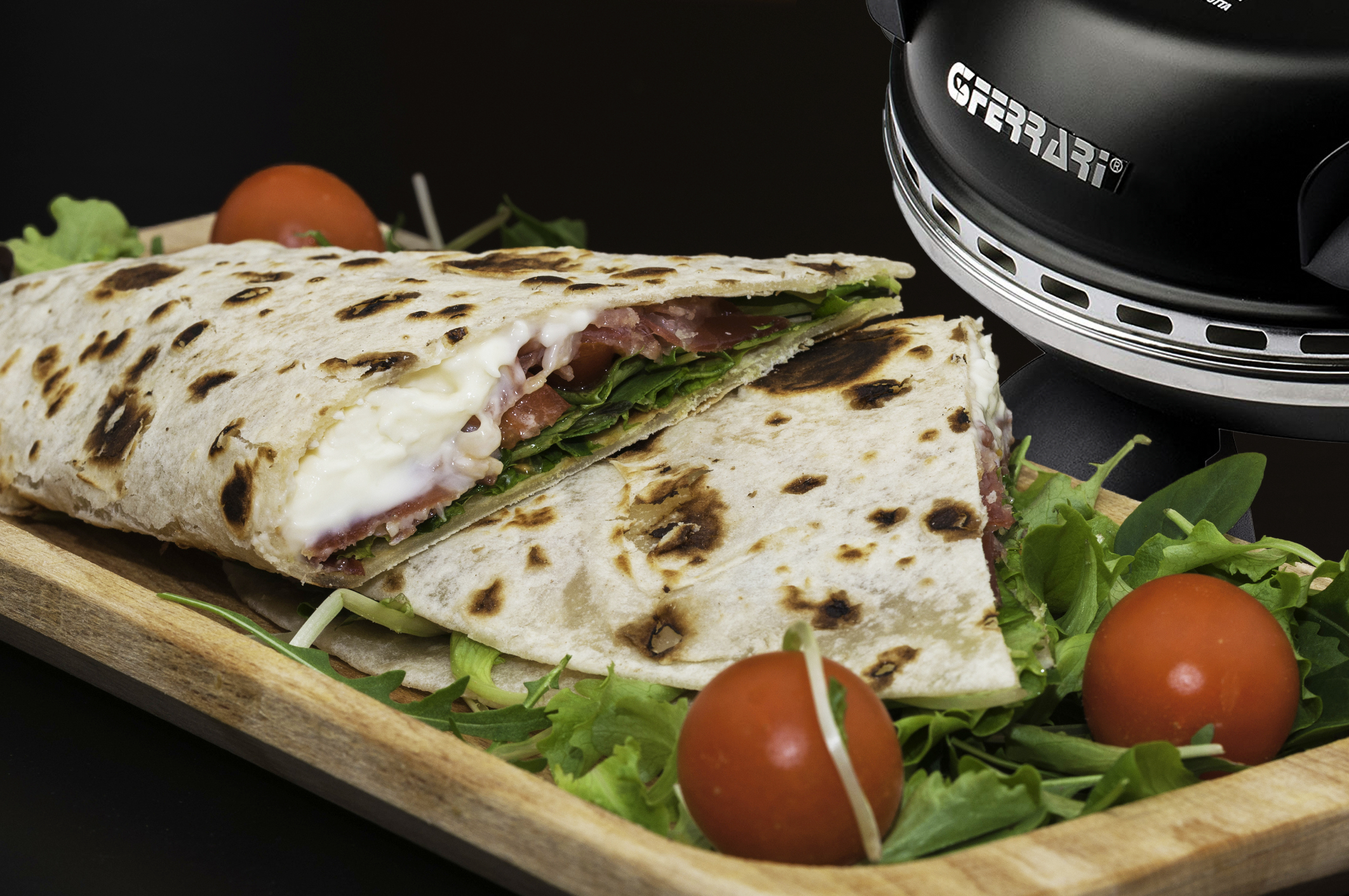 Aufgeschnittenes Fladenbrot-Sandwich, gefüllt mit weißem Käse, Fleisch und grünen Blättern, auf einem Holzbrett.