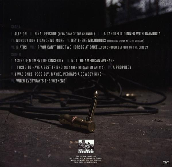 Zenei CD hátoldala számlistával és sötét, összegubancolódott gitárkábellel a padlón.