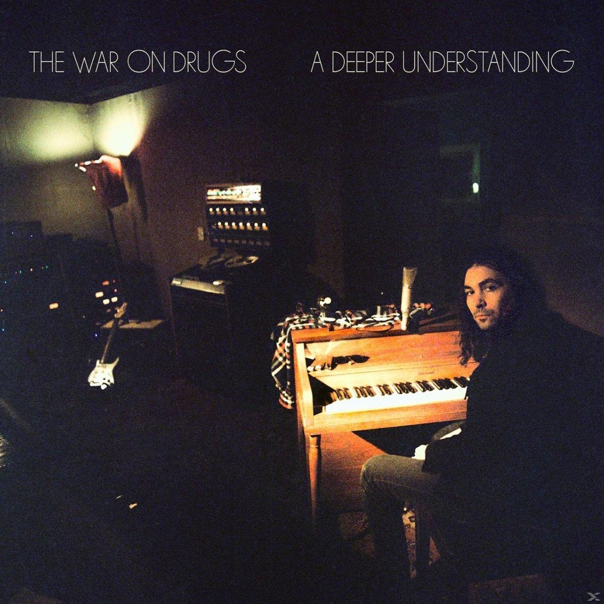 A The War on Drugs 'A Deeper Understanding' című albumának borítója, egy férfival, aki zongorázik egy sötét szobában.