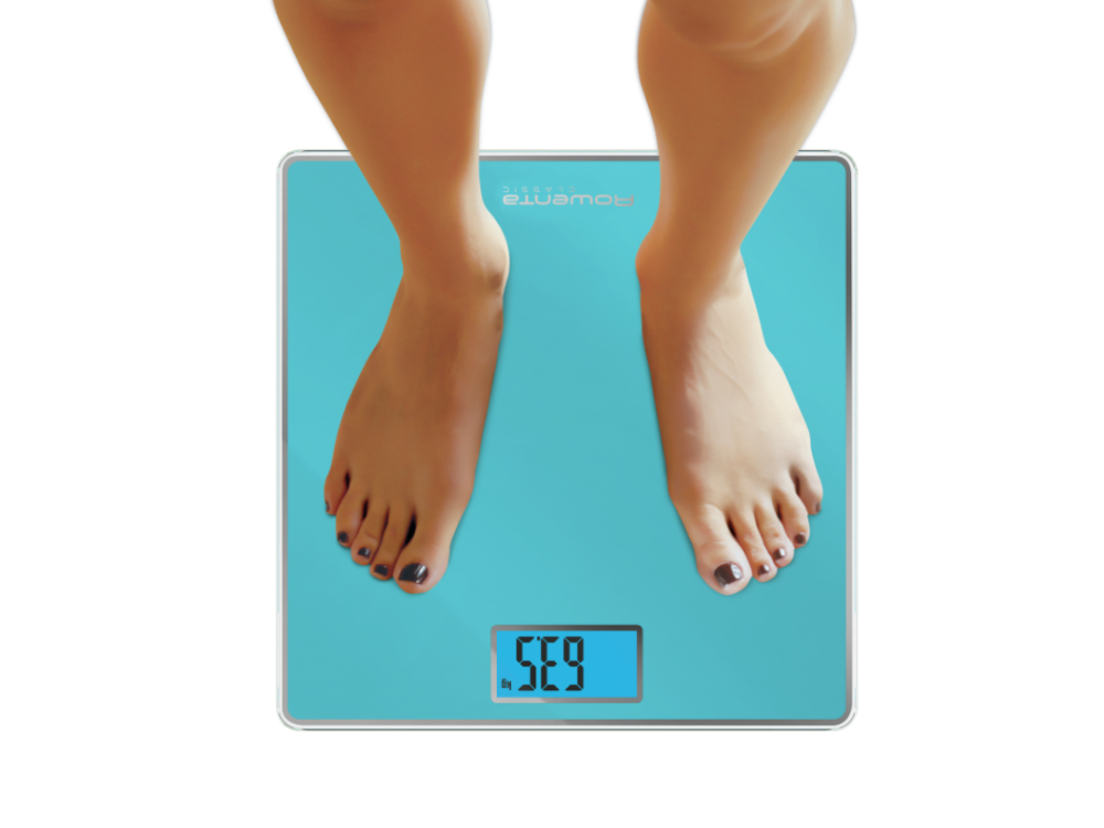 Pies de una persona sobre una báscula digital turquesa, mostrando un peso de 56.9.