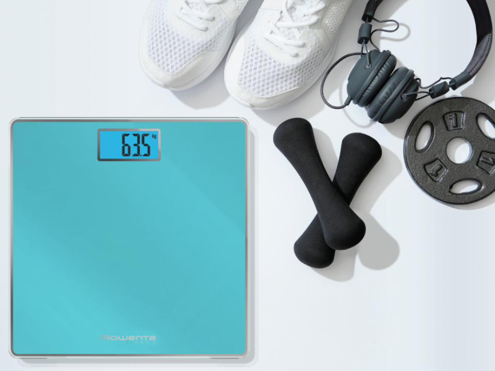 Báscula digital muestra 63.5, con pesas y auriculares alrededor.