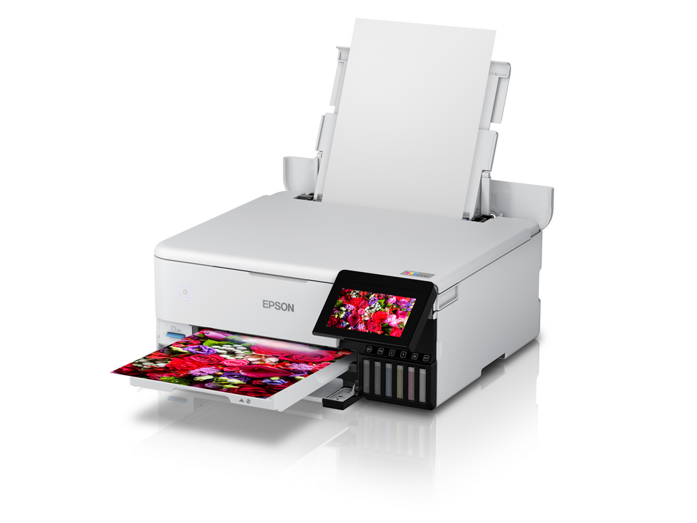 Impresora blanca con pantalla a color, bandeja de papel y salida de impresión colorida.