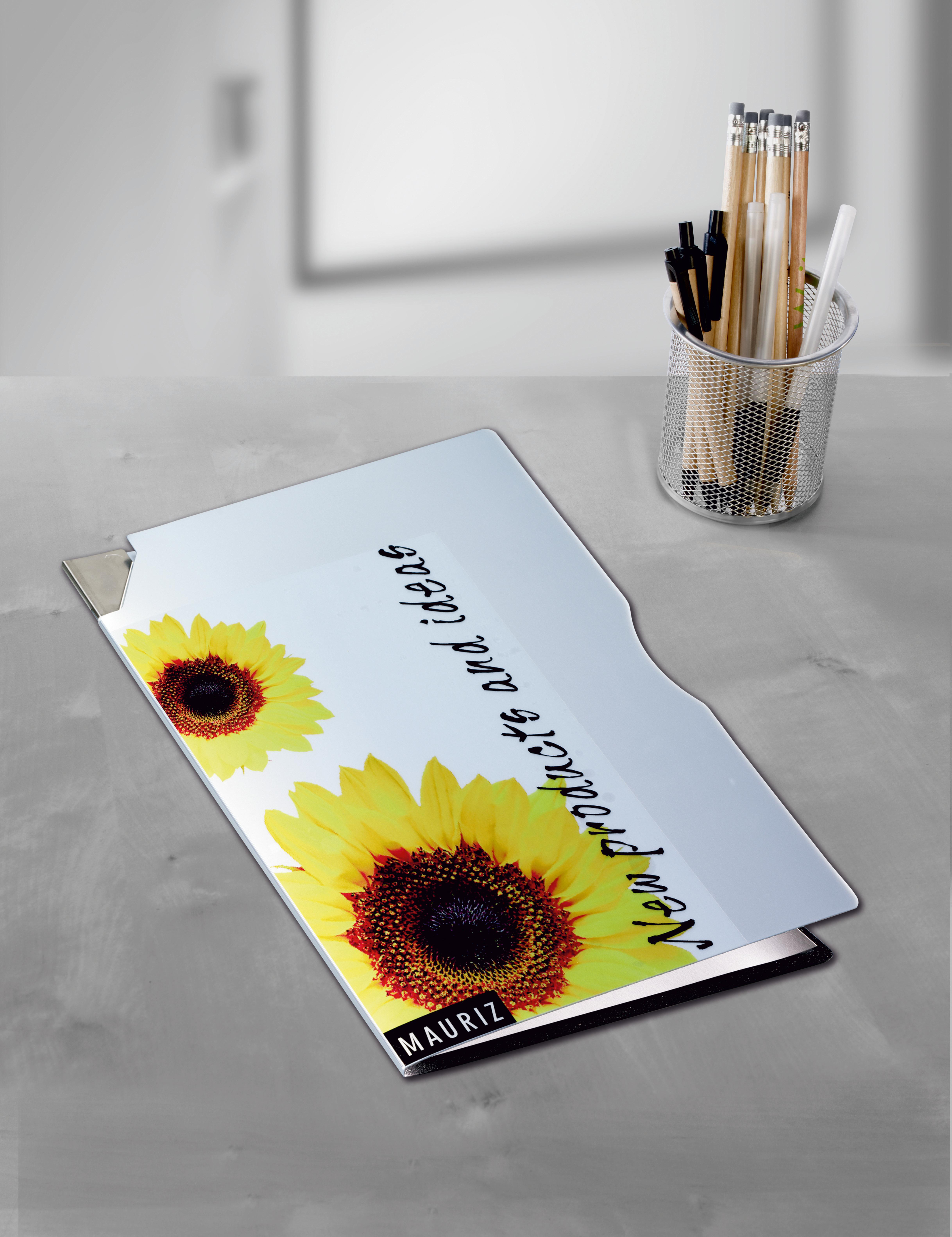 Ein Schreibtisch mit einem Ordner mit Sonnenblumen und Text, sowie Bleistiften in einem Metallbecher.