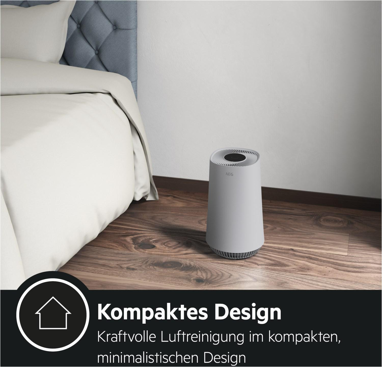 Ein weißer Luftreiniger steht auf einem Holzboden neben einem Bett.