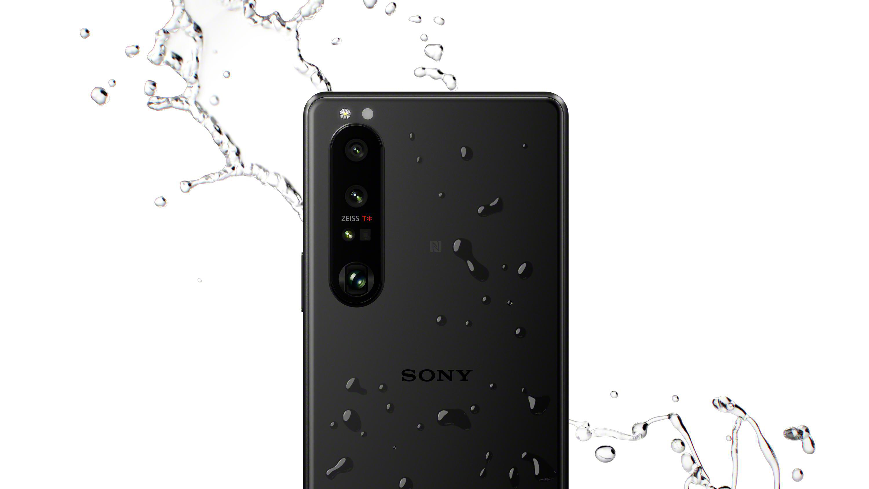 Nahaufnahme eines schwarzen Smartphones mit Wassertropfen.