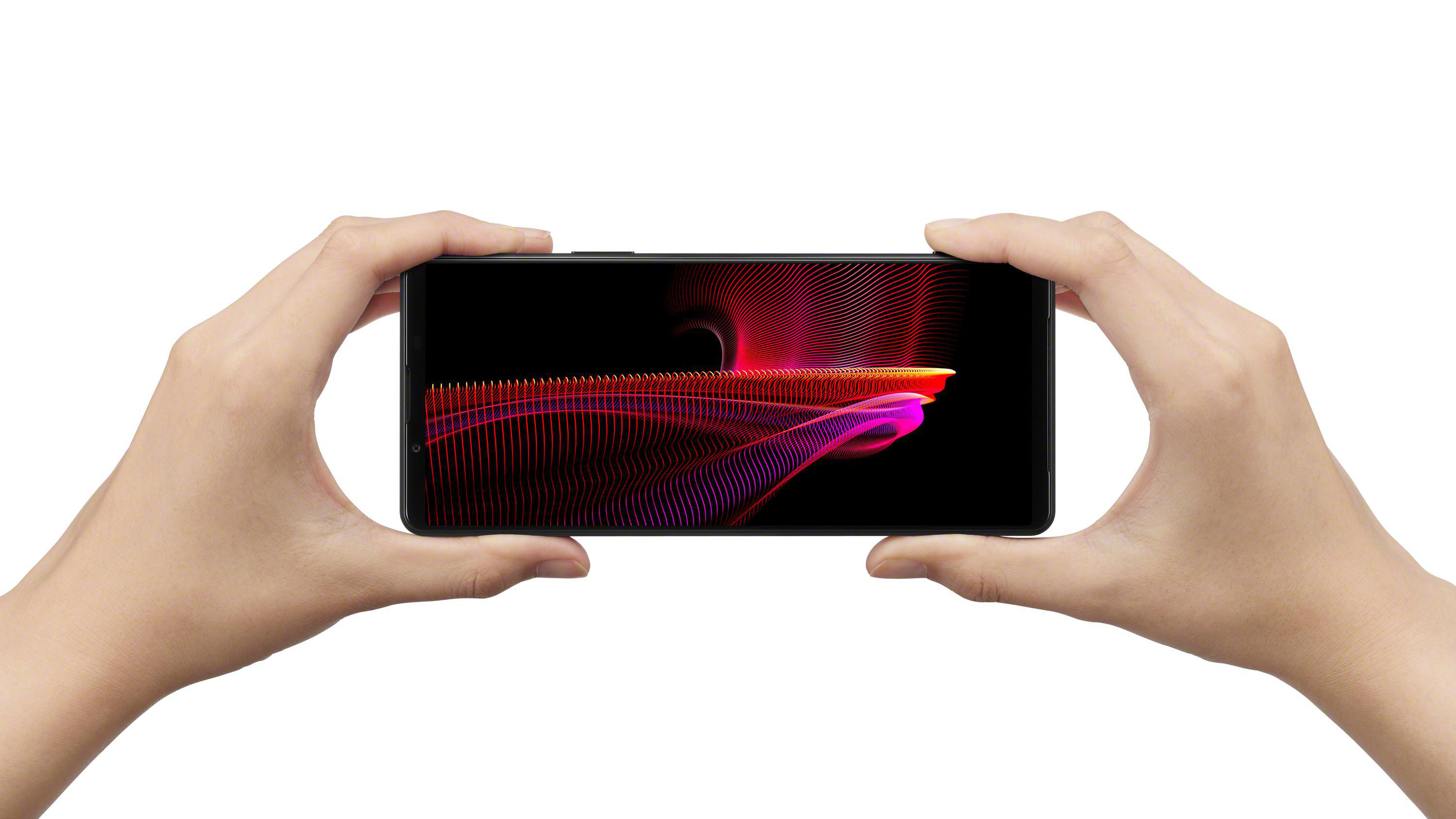 Hände halten ein Smartphone, das eine farbenfrohe, abstrakte Grafik auf schwarzem Hintergrund zeigt.